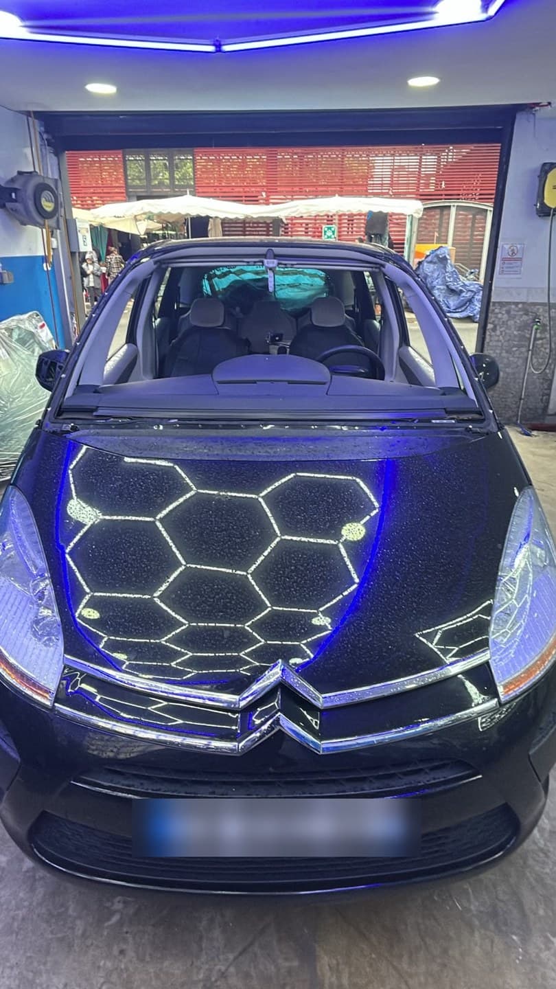 Citroën C4 Picasso noir en atelier, pare-brise déposé : on voit la baie entièrement dégagée avant la pose