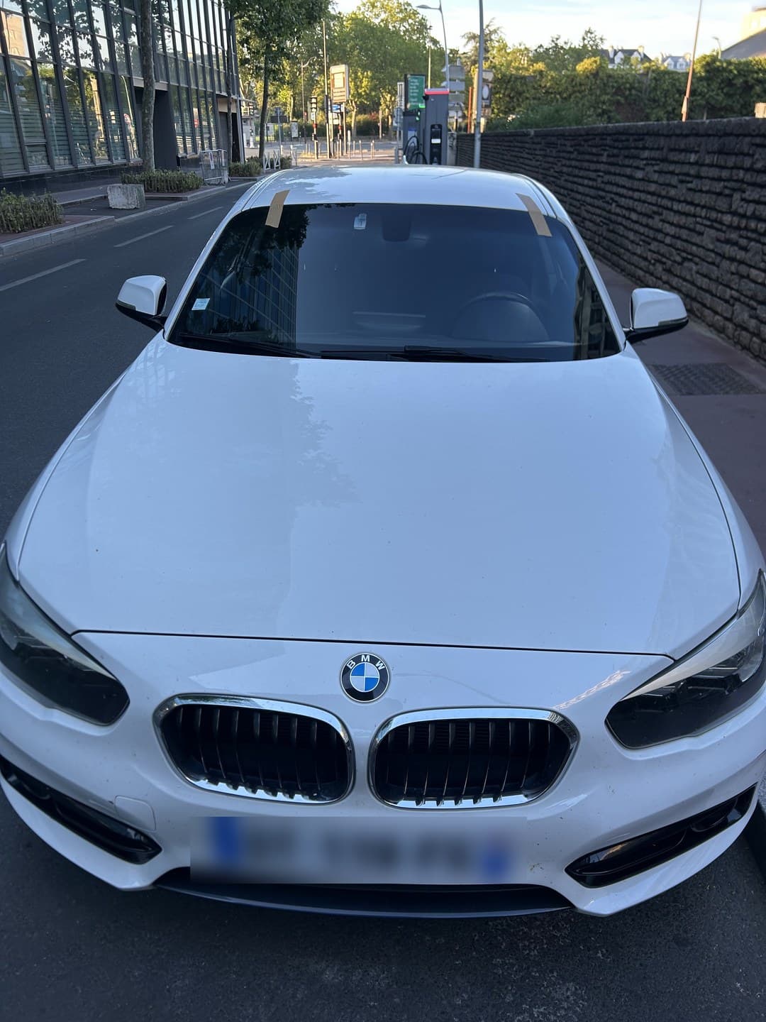 BMW Série 1 blanche, pare-brise neuf posé, adhésifs de maintien en haut de baie