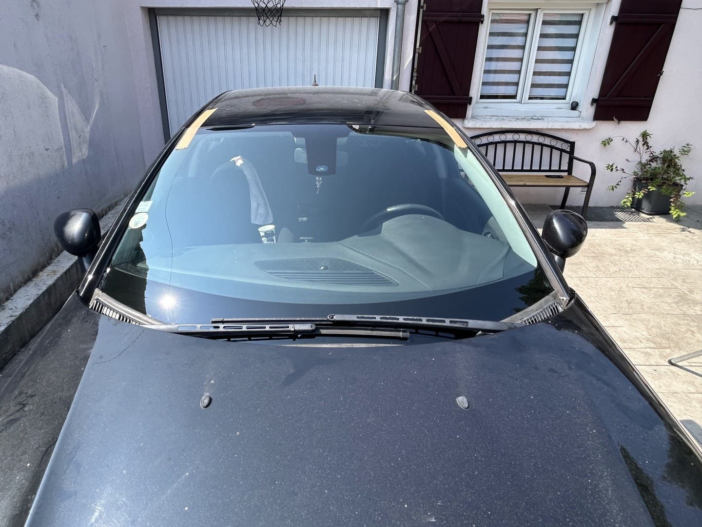 Citroën C5 noire dans la cour du client, pare-brise neuf posé, adhésifs de maintien en haut de baie