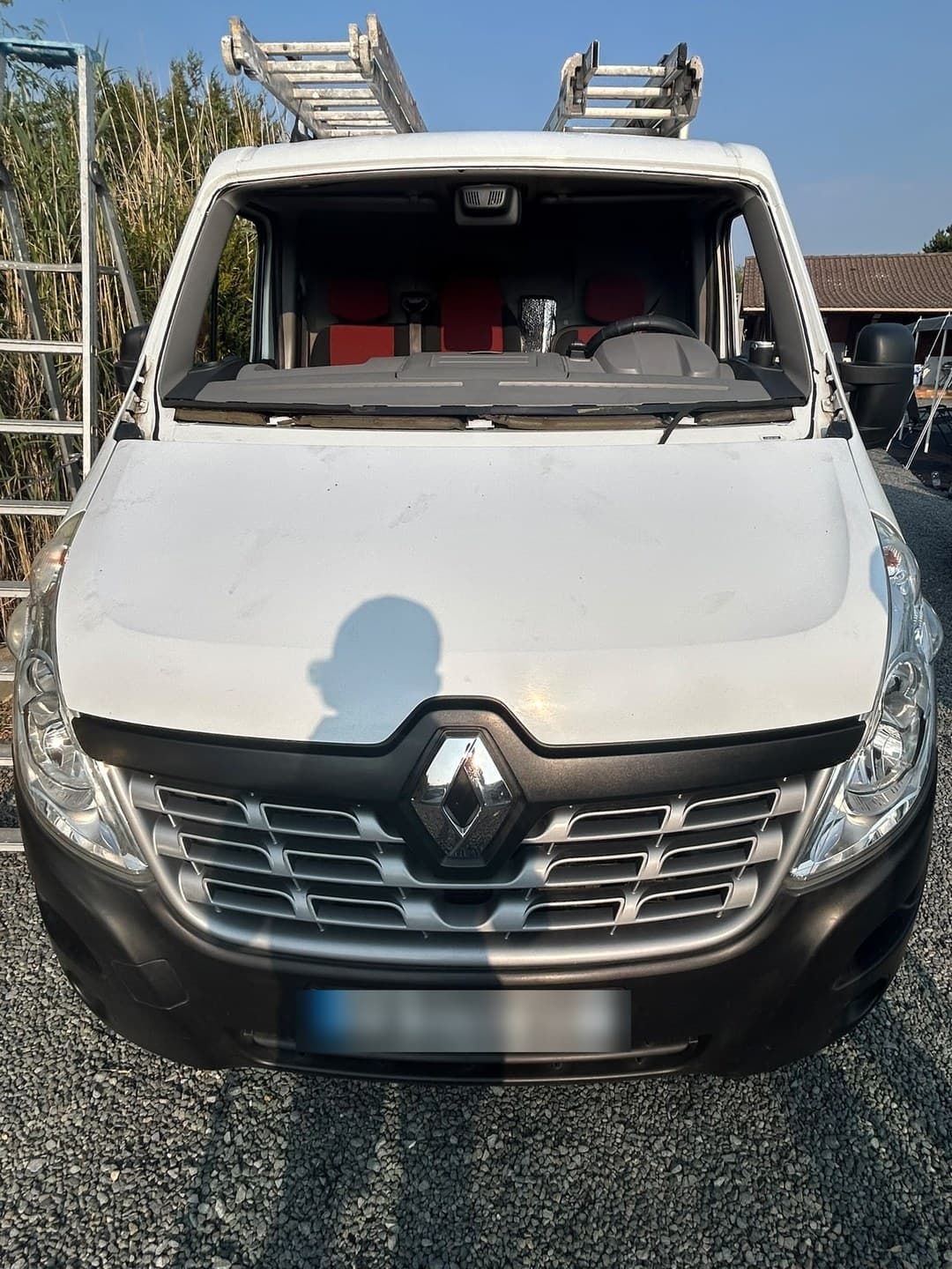 Renault Master blanc, pare-brise déposé : le véhicule de chantier garde ses échelles sur le toit pendant l'intervention