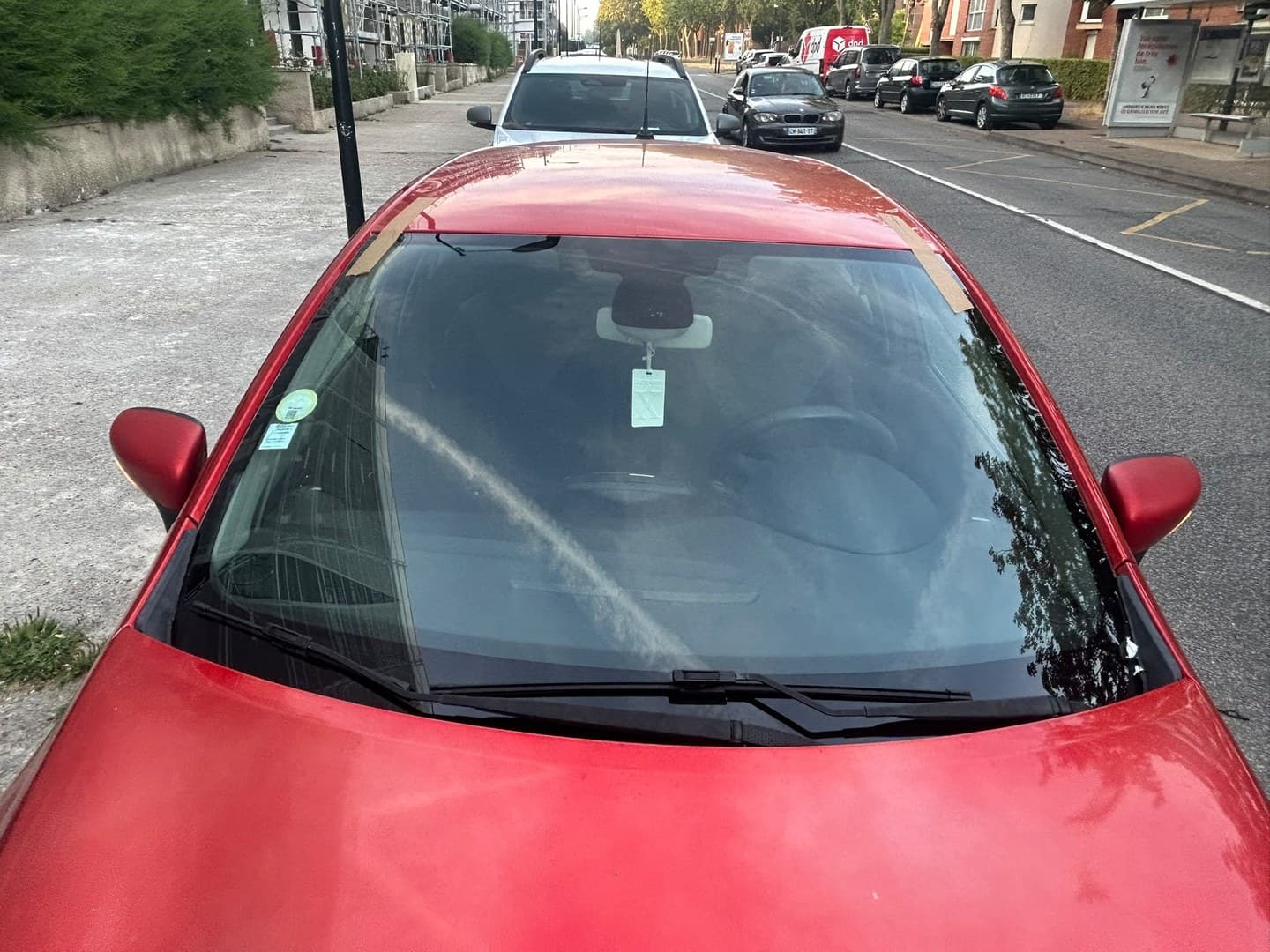 Renault Clio IV rouge, pare-brise neuf posé et maintenu par adhésifs, intervention en bord de rue