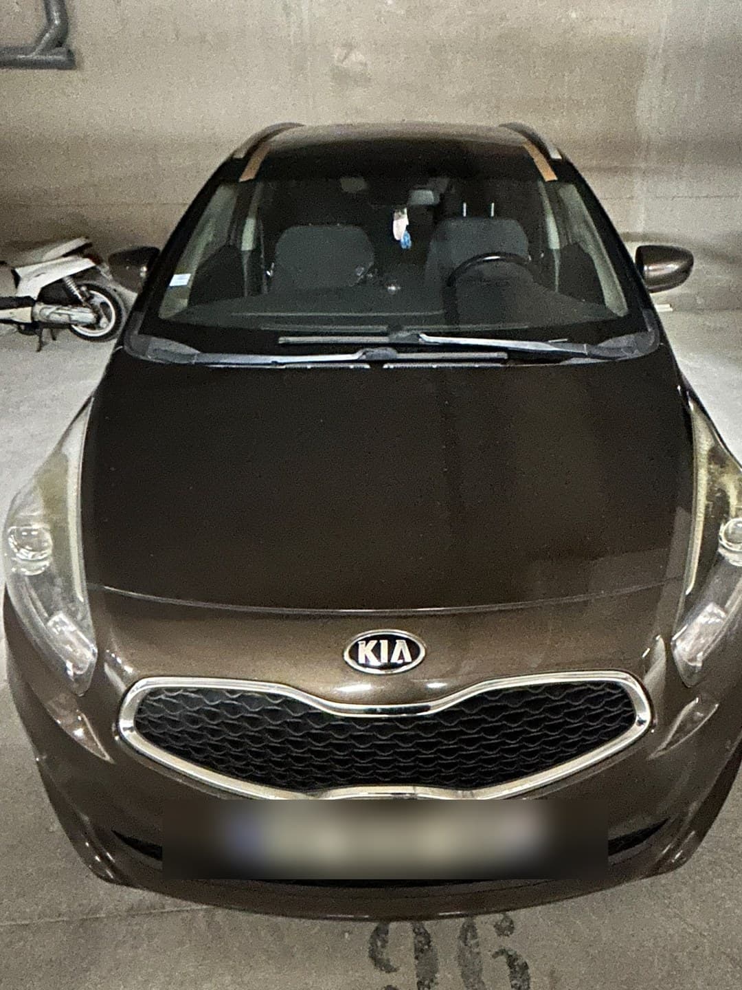 Kia Ceed SW marron en parking souterrain, pare-brise neuf posé, adhésifs de maintien en haut de baie