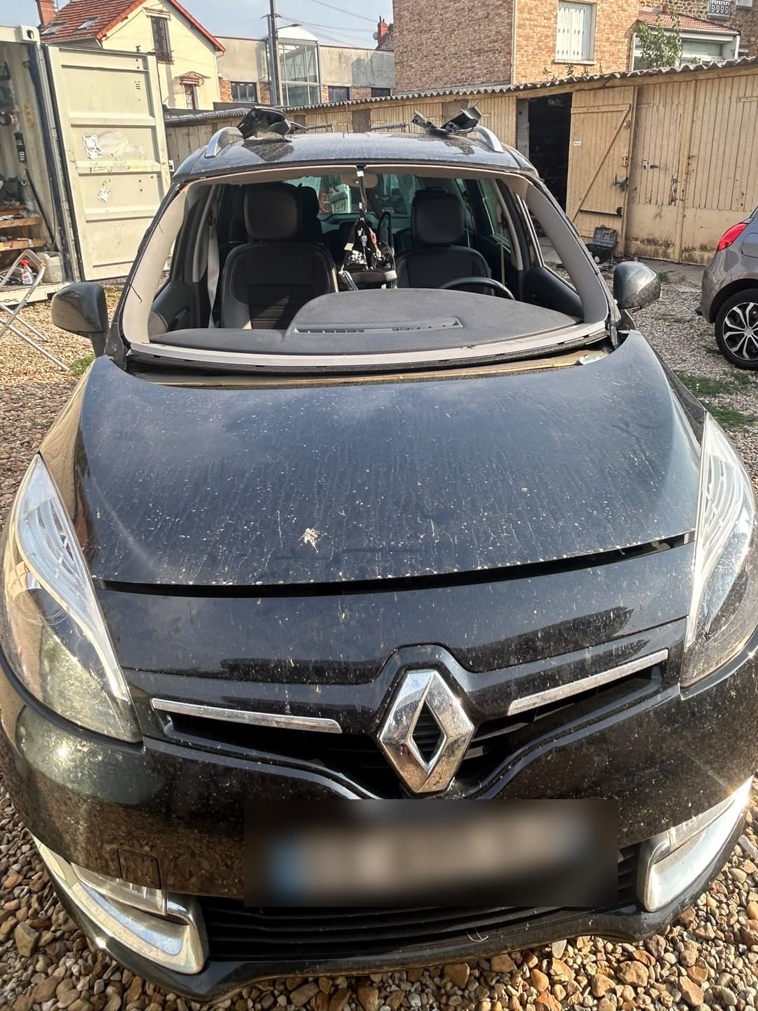 Renault Grand Scénic noir, pare-brise déposé, intervention devant le local du client