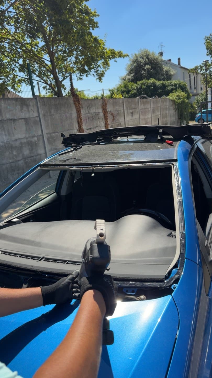 Toyota Auris bleue, pare-brise déposé : découpe de l'ancien cordon de colle sur la baie