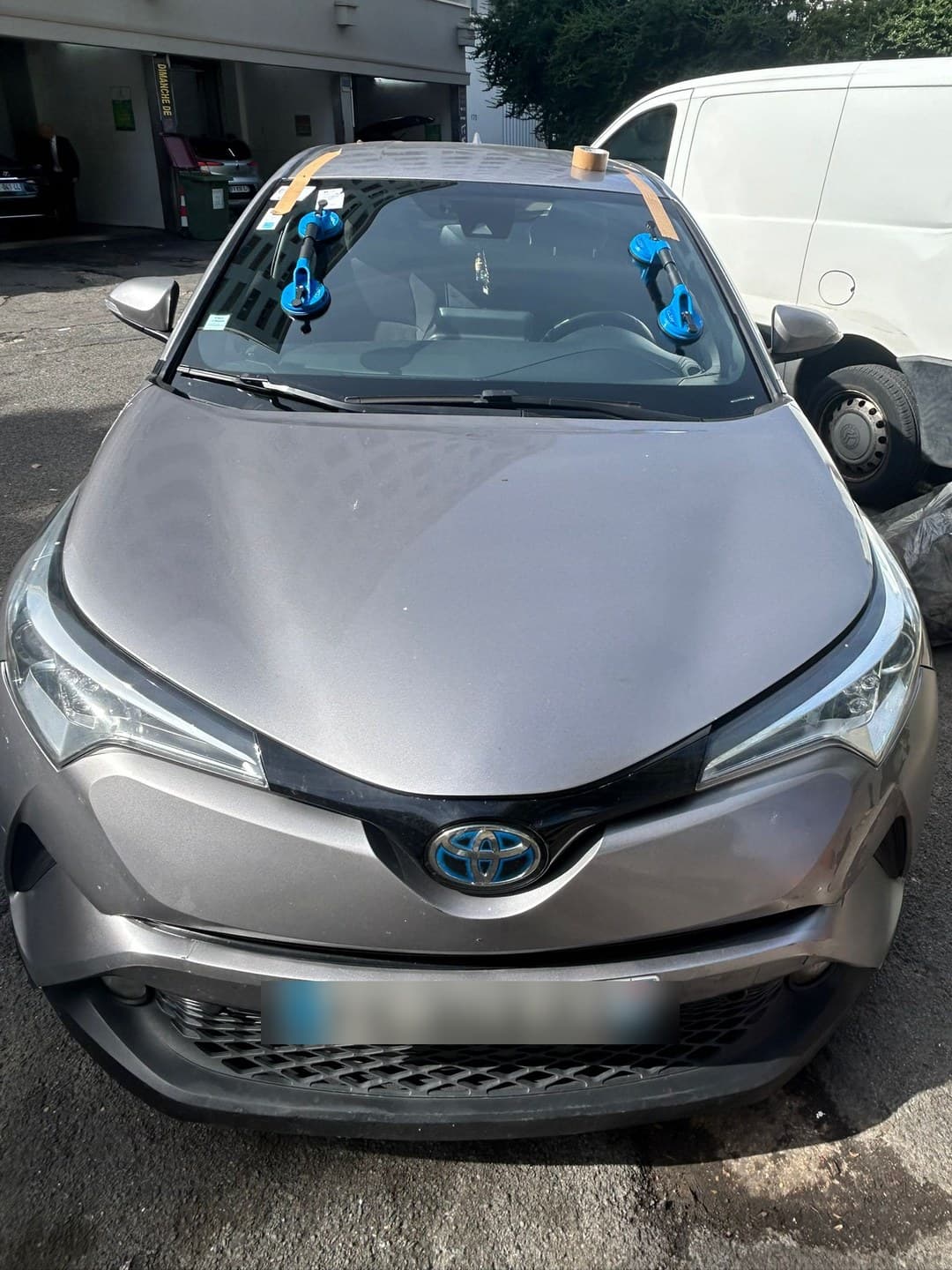 Toyota C-HR hybride gris, pare-brise neuf posé, ventouses et adhésifs de maintien encore en place
